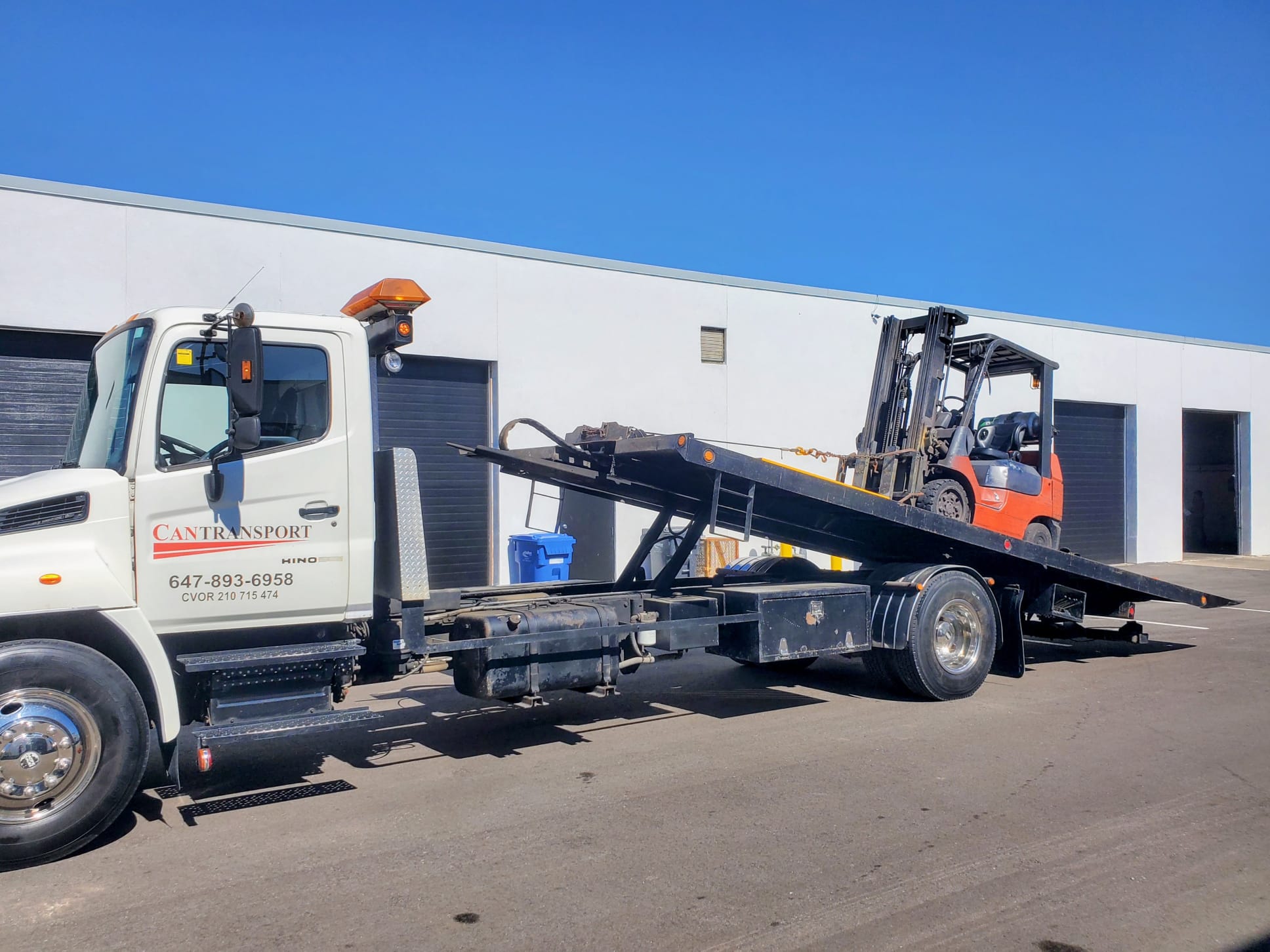 Toyota forklift loading onto tilt-deck truck